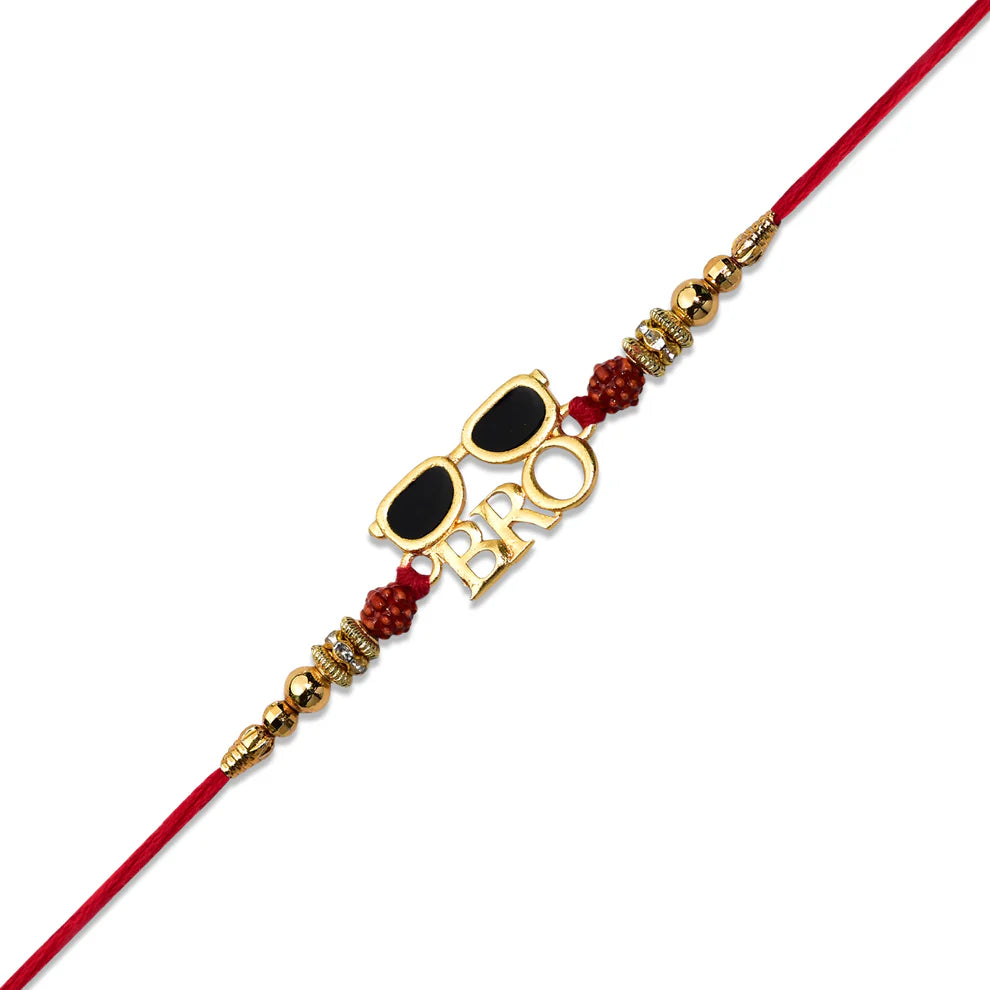 A red string rakhi bracelet with a gold-tone 'BRO' letter charm, gold sunglasses charm, and red beaded accents, shown on a plain white background.