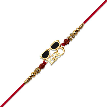 A red string rakhi bracelet with a gold-tone 'BRO' letter charm, gold sunglasses charm, and red beaded accents, shown on a plain white background.