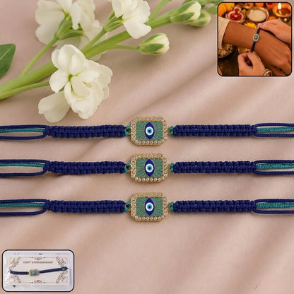 Three blue braided Rakhi bracelets with gold-toned evil eye pendants are arranged on a beige fabric background with white flowers. A small inset shows the bracelet being worn on a wrist, and a packaging card is visible in the lower left corner.